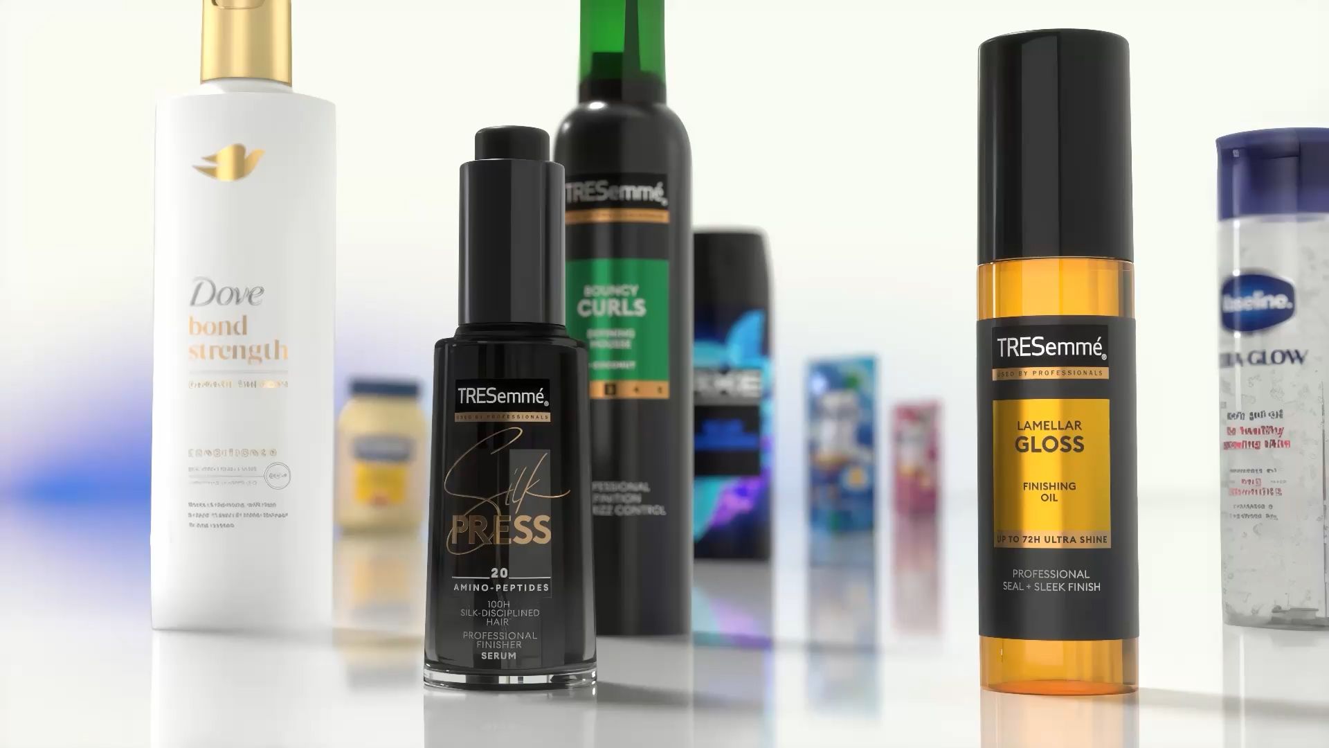 Imagem em close-up de diversos produtos para cabelo e corpo expostos em uma superfície refletora. Os itens visíveis incluem o condicionador Dove Bond Strength, o sérum TRESemmé Silk Press, o óleo finalizador TRESemmé Lamellar Gloss e outros produtos da Unilever ao fundo.